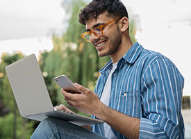 Image student on campus looking at the cell phone with laptop open