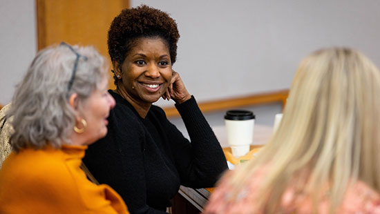 Serena Simpson, IT Communication specialist talks with colleagues before an extended staff meeting