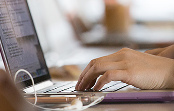 Hands typing on a laptop