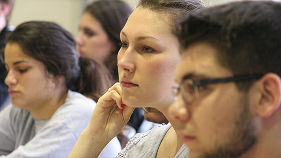 Students seated in a classroom, attentively facing forward.