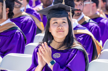 Northwestern graduate in cap and gown clapping