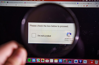 A person using a magnifying glass to see a CAPTCHA.