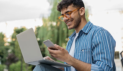 Image student on campus looking at the cell phone with laptop open