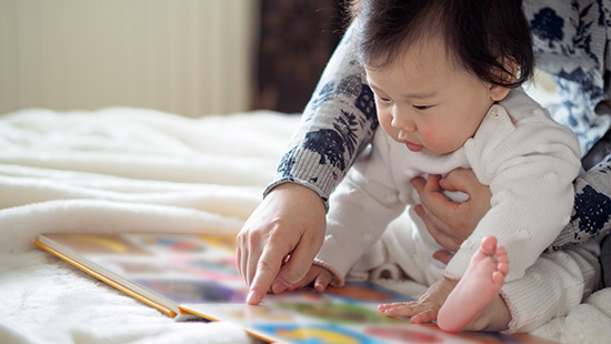 Baby girl reading book with mom stock photo