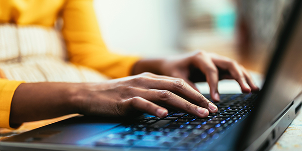 Close-up of hands typing on a laptop keyboard.